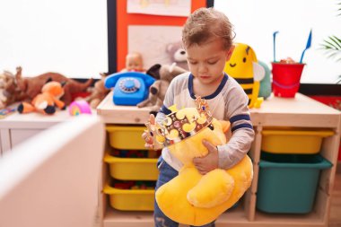 Beyaz çocuk anaokulunda oyuncak ördekle oynuyor.