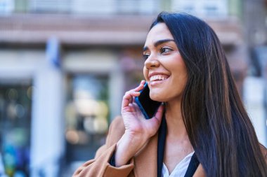 Genç İspanyol kadın gülümsüyor. Kendine güveniyor. Akıllı telefondan konuşuyor.