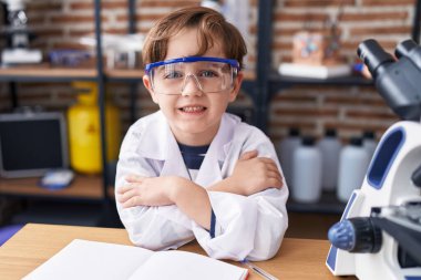 Sevimli İspanyol çocuk gülümsüyor. Kollarını kavuşturup laboratuvar sınıfına gidiyor.