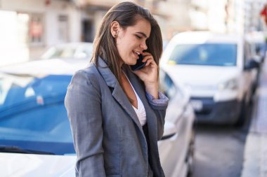 Gülümseyen genç bir kadın caddedeki akıllı telefondan konuşuyor.