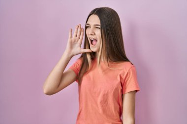 Pembe arka planda duran genç kız el ele verip bağırarak ve yüksek sesle bağırıyor. iletişim konsepti. 