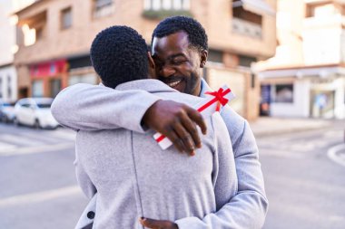 Erkek ve kadın çift sokakta birbirlerine sürpriz bir şekilde sarılıyorlar.