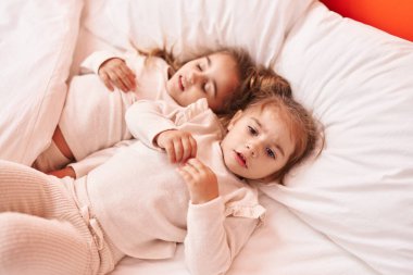 Yatak odasında iki çocuk yatıyor.