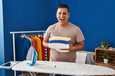 İspanyol genç adam ütü yaptıktan sonra çamaşırları katladı. Güldü ve güldü. Çünkü çok komik bir şakaydı.. 