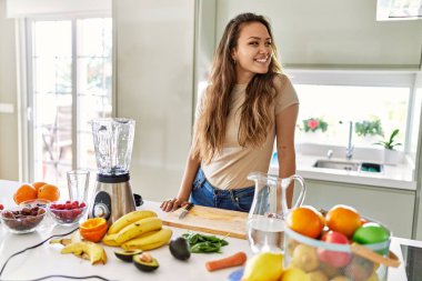 Genç, güzel İspanyol kadın mutfakta sebze suyu ve blender hazırlıyor.