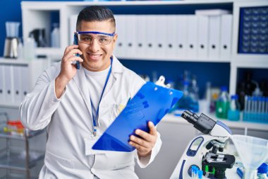 Genç Latin bilim adamı laboratuvarda akıllı telefon okuyarak konuşuyor.