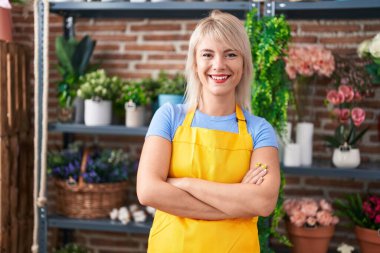 Young blonde woman florist smiling confident standing with arms crossed gesture at florist