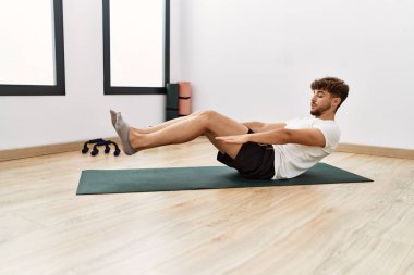 Young arab man training abs exercise at sport center