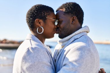 Erkek ve kadın çift deniz kenarında öpüşüyorlar.