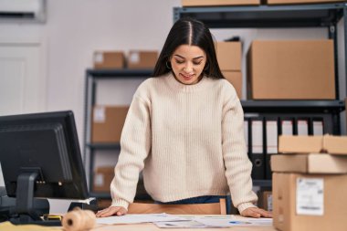 Young beautiful hispanic woman ecommerce business worker reading document at office
