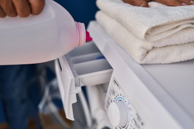 Senior man pouring detergent on washing machine at laundry room
