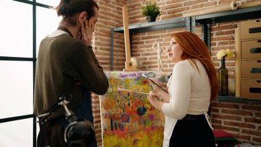 Bir erkek ve bir kadın resim stüdyosunda konuşuyor.