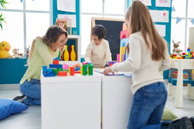 Group of kids playing with maths puzzle game with teacher at kindergarten