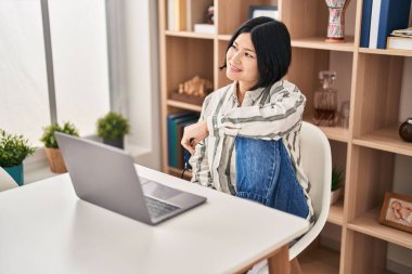 Young chinese woman using laptop sitting on table at home