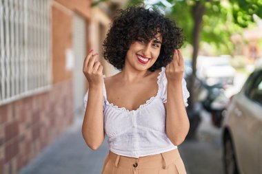 Orta Doğulu genç bir kadın gülerek para harcıyor.