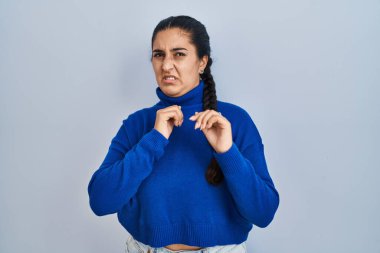 Soyutlanmış arka planda duran Latin kökenli genç bir kadın tiksinti dolu bir yüz ifadesi, tiksinti dolu bir yüz ifadesi.. 