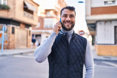 Genç İspanyol adam gülümsüyor. Kendine güveniyor. Sokakta akıllı telefondan konuşuyor.