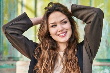 Young beautiful hispanic woman relaxed with hands on head looking to the side at street