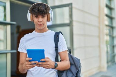 Latin kökenli genç bir öğrenci üniversitede müzik dinlerken touchpad kullanıyor.