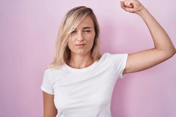 Young Blonde Woman Standing Pink Background Strong Person Showing Arm — Stockfoto