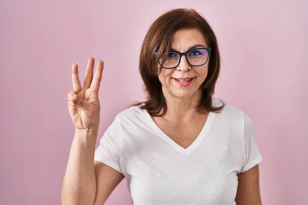 中年惊慌失措的女人站在粉红的背景上 用第三根手指指指着 满面笑容 自信而快乐 — 图库照片
