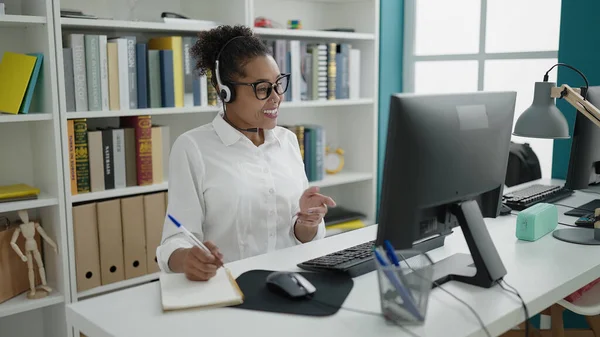 アフリカ系アメリカ人の女性教師が図書館大学のノートにビデオ通話を書く — ストック写真
