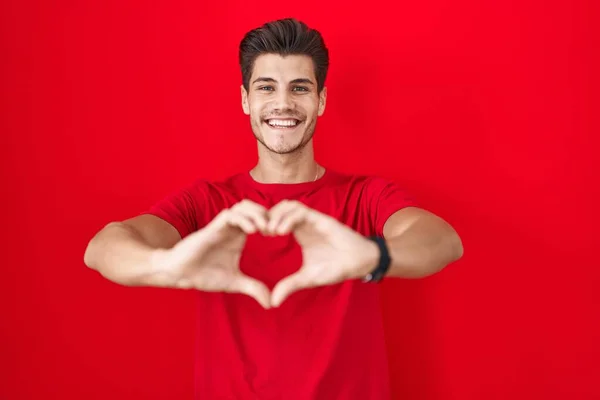 Homem Hispânico Jovem Sobre Fundo Vermelho Sorrindo Amor Fazendo Forma — Fotografia de Stock