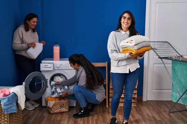 Three woman washing clothes at laundry room
