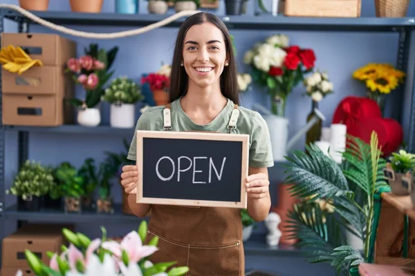 Young brunette woman working at florist holding open sign smiling with a happy and cool smile on face. showing teeth.