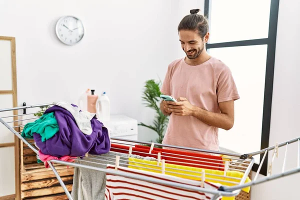 Handsome Hispanic Man Hanging Laundry Using Smartphone Laundry Room — Stock Photo, Image