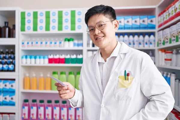 Młody Chińczyk Aptekarz Uśmiecha Się Pewnie Czytając Receptę Aptece — Zdjęcie stockowe