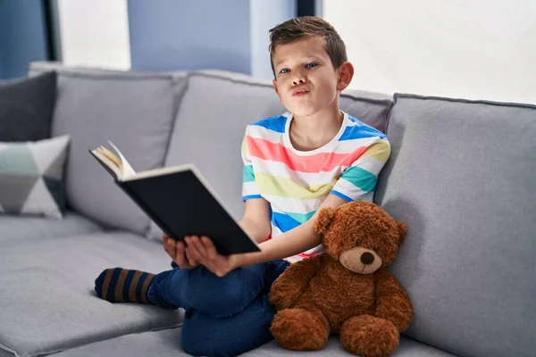 Genç Beyaz Bir Çocuk Kanepede Oturmuş Kitap Okuyor Kameraya Bakıyor — Stok fotoğraf