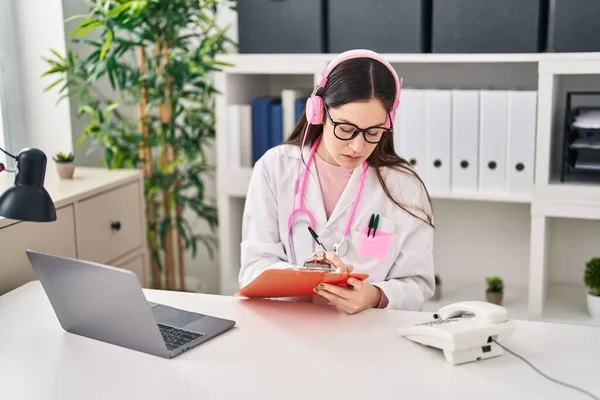 Young woman wearing doctor uniform listening to music working at clinic