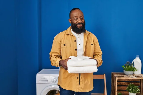 African American Man Holding Clean Towels Laundry Room Winking Looking — Foto de Stock
