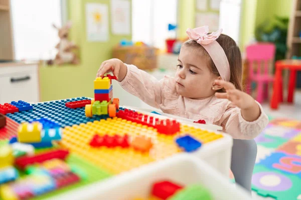 stock image Adorable blonde toddler playing with construction blocks sitting on table at kindergarten