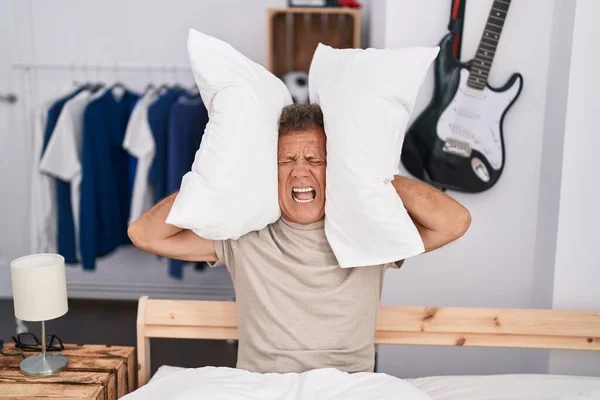 Middle age man covering ears for noise at bedroom