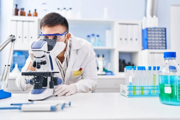 Young Hispanic Man Scientist Using Microscope Wearing Medical Mask Laboratory — Stock Photo, Image