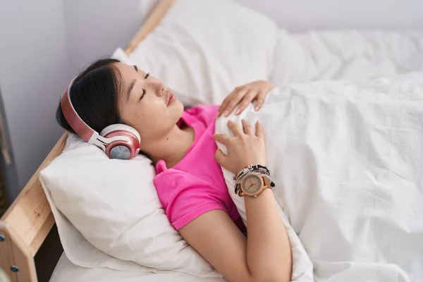 Chinese woman listening to music sleeping on bed at bedroom