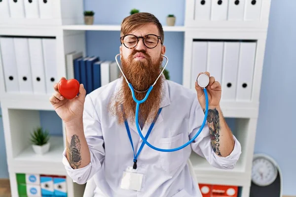 Redhead Man Med Långt Skägg Bär Läkare Uniform Hålla Hjärta — Stockfoto