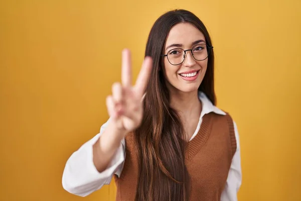 Young Brunette Woman Standing Yellow Background Wearing Glasses Smiling Looking — Stock Photo, Image