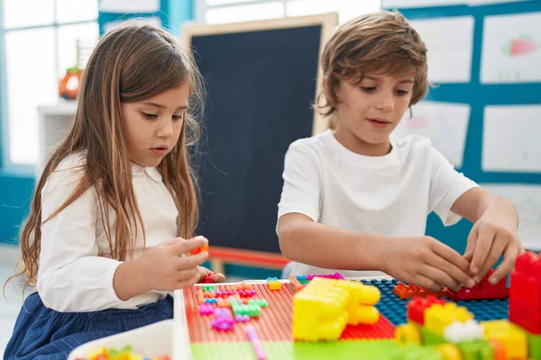 stock image Brother and sister playing with construction blocks sitting on table at kindergarten