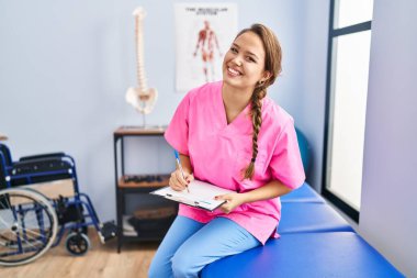 Genç ve güzel İspanyol fizyoterapist. Rehabilitasyon kliniğinde kendine güvenen bir yazı.