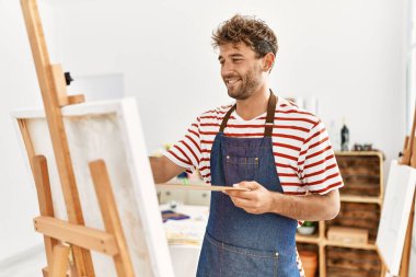 Genç İspanyol adam resim stüdyosunda kendine güvenen gülümsüyor.