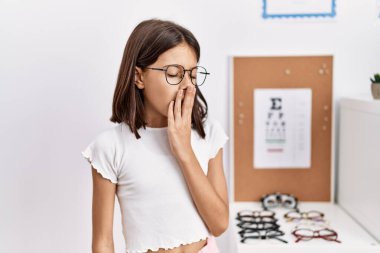 Young hispanic girl wearing glasses bored yawning tired covering mouth with hand. restless and sleepiness. 