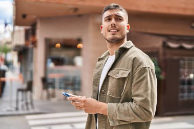 Sokakta akıllı telefon kullanan genç bir İspanyol.