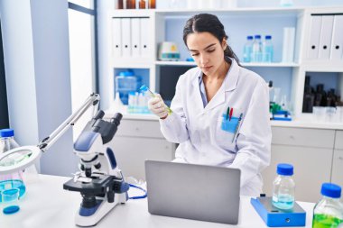 Laboratuvarda çalışan, bilim adamı üniforması giyen genç İspanyol kadın.