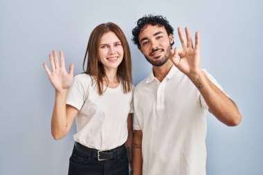 Young couple wearing casual clothes standing together showing and pointing up with fingers number eight while smiling confident and happy. 