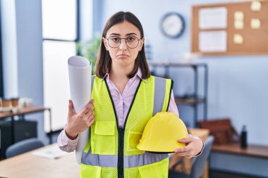 Hispanic girl architect holding build project blueprints depressed and worry for distress, crying angry and afraid. sad expression. 