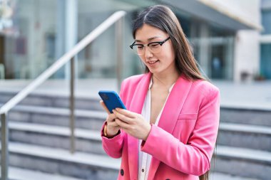 Sokakta akıllı telefon kullanan Çinli bir iş kadını.