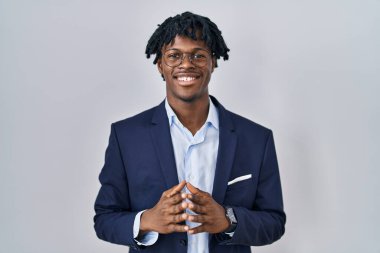 Young african man with dreadlocks wearing business jacket over white background hands together and fingers crossed smiling relaxed and cheerful. success and optimistic 